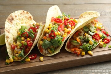 Tasty vegetarian tacos with chickpeas, corn and quinoa served on wooden table, closeup