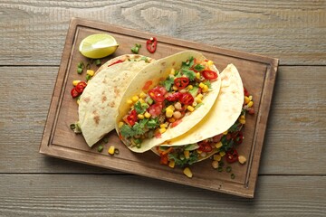 Tasty vegetarian tacos with chickpeas, corn and quinoa served on wooden table, top view
