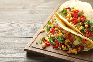 Tasty vegetarian tacos with chickpeas, corn and quinoa served on wooden table, closeup. Space for text
