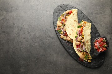 Tasty vegetarian tacos with beans and quinoa served on grey table, top view. Space for text