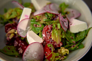 A Fresh and Colorful Salad Featuring Mixed Greens, Cherry Tomatoes, Radishes, Quinoa, and Creamy Cheese in a Beautiful Bowl Presentation