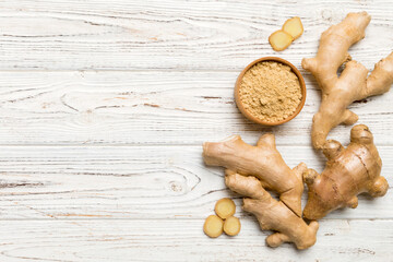 Fototapeta premium Finely dry Ginger powder in bowl with green leaves isolated on colored background. top view flat lay
