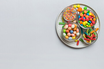 Multicolored candies in a bowl on a colored background. birthday and holiday concept. Top view with...