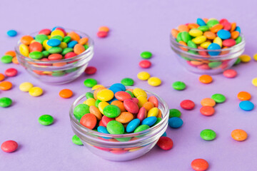 Multicolored candies in a bowl on a colored background. birthday and holiday concept. Top view with...