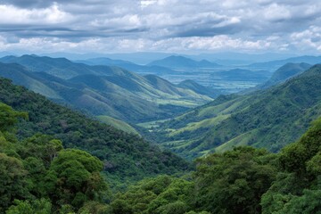 Naklejka premium Vast verdant mountain valley under a dramatic cloudy sky with lush greenery and rolling hills