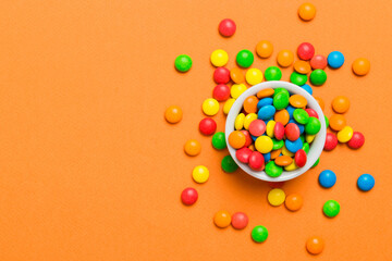 Multicolored candies in a bowl on a colored background. birthday and holiday concept. Top view with...