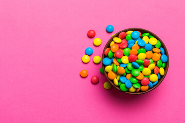 Obraz premium Multicolored candies in a bowl on a colored background. birthday and holiday concept. Top view with copy space