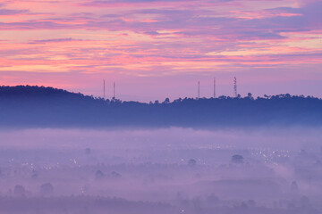 A serene landscape enveloped in a soft, misty atmosphere under a vibrant, colorful sky