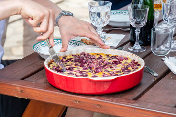 Clafoutis aux cerises fait maison servi sur une table en bois pendant un repas convivial en extérieur