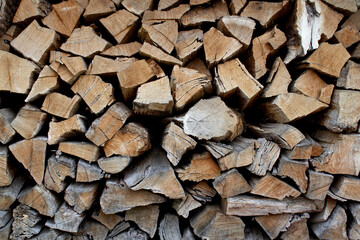 Large pile of firewood, cut of wood, dark texture group of objects close up