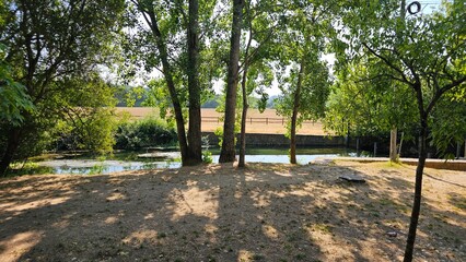 Tranquil Shaded Riverside with Green Trees and Stone Wall