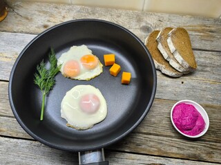 Top view of a frying pan with a breakfast of fried eggs and delicious bacon and various seasonings