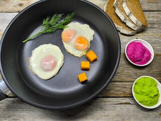 Top view of a frying pan with a breakfast of fried eggs and delicious bacon and various seasonings