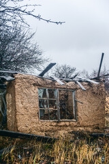 an old, ruined clay house with debris and other debris scattered around it, against a stormy sky