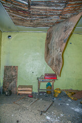 the interior of an old house from the post-Soviet era, with trash, furniture and a hanging ceiling scattered around