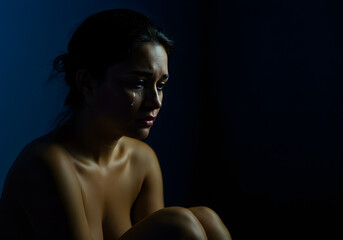 Naked woman crying in the dark.