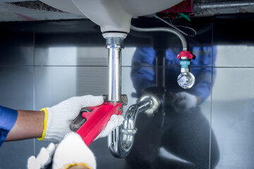Plumber hands holding wrench doing repairing work at the sink and clogged pipe in bathroom carefully