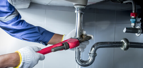 Plumber hands holding wrench doing repairing work at the sink and clogged pipe in bathroom carefully