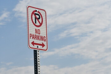 No parking sign, angled shot with bright blue sky.