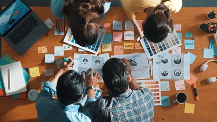 Top view of business team write graphic logo on meeting table with colorful sticky notes and design...