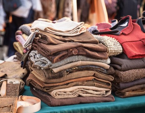 a pile of vintage clothing on a table at a flea market - Powered by Adobe