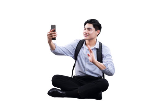 Man in Conversation: A young man, cross-legged and engrossed, holds a smartphone, seemingly engaged in a video call, exuding modern connection.