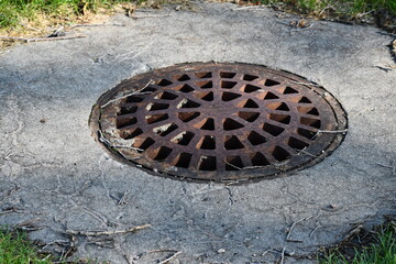Large round drainage grate in city park. Grate inverts slightly upward.