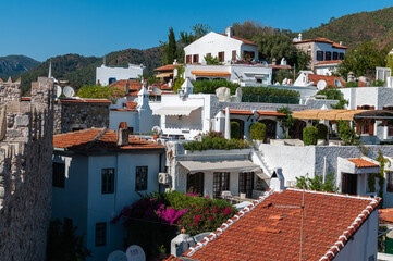 Picturesque white Mediterranean style houses with red tiled roofs and terraces with lush vegetation and flowers in the city of Marmaris
