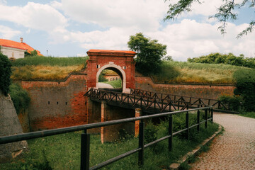 Historic red-brick gate and wooden bridge at Petrovaradin Fortress in Novi Sad, Serbia, surrounded...