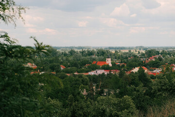 Scenic view of a Serbian town with red rooftops and a church tower surrounded by lush greenery,...