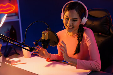 Smiling creative young beautiful Asian influencer talking in channel with positive podcast speech...