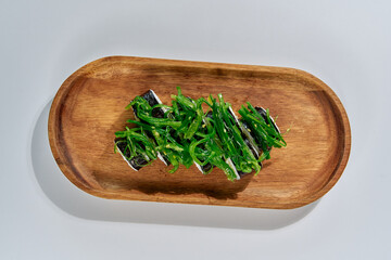 Delicious Green Seaweed Salad Arranged Artistically on a Wooden Tray for a Healthy and Colorful...