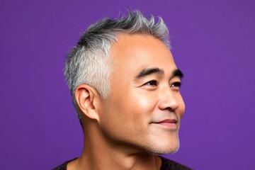 Fototapeta premium Visual idea of style for aging men. A modern man in his 40s with a stylish appearance. Purple solid background. Elegant men's wavy fringe haircut - midlife southeast asian man with short hair.