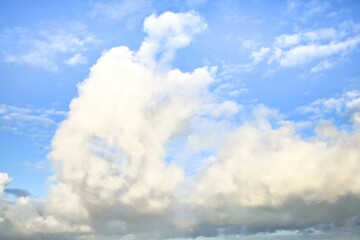 Sky replacement of some light grey puffy clouds with a light blue sky behind them.