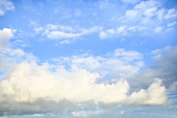 Sky replacement of some light grey puffy clouds with a light blue sky behind them.