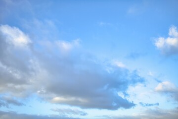 Sky replacement of some light grey puffy clouds with a light blue sky behind them.
