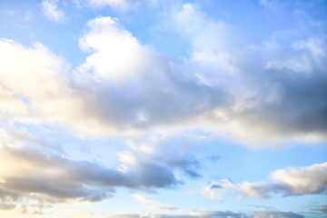 Sky replacement of some light grey puffy clouds with a light blue sky behind them.