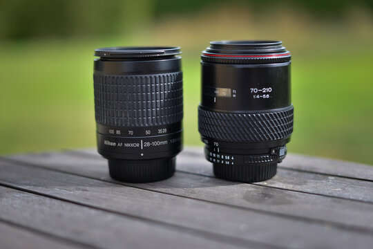Copenhagen, Denmark - September 13, 2021: Nikon zoom lens and Tamron telephoto lens on wooden table in outdoor setting during daylight