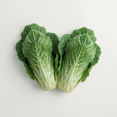 Two vibrant heads of crisp green lettuce are artfully positioned to form a heart shape on a bright white surface