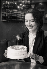 Smiling woman holding a birthday cake with a sparkler