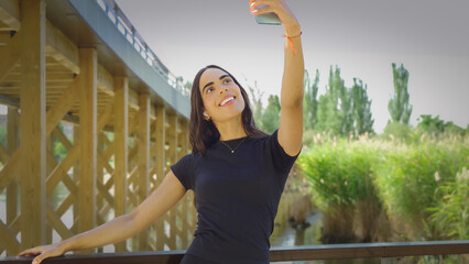 Smiling young woman taking a selfie with smartphone in a city park