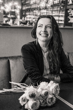 Smiling woman with flowers in a cafe, black and white portrait