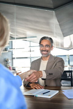 Mature smiling happy professional business man executive, male hr recruiter or bank manager hiring recruit at job interview onboarding corporate office meeting. Handshake with new client. Vertical