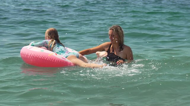 Woman child swimming, ocean inflatable fun, playful summer vacation
