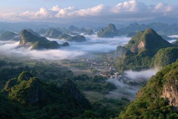Misty morning over lush green karst mountains revealing a serene village nestled below