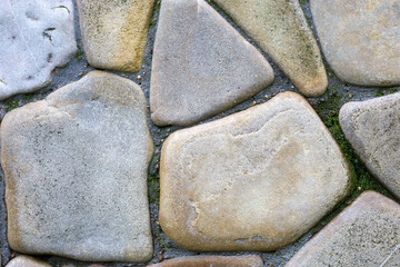 Variously colored stones, tightly laid and separated by moss, form a natural pattern. Smooth...