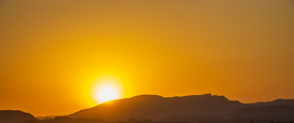 Stunning sunset over the mountains in Alicante, creating a warm golden hue over the landscape,...