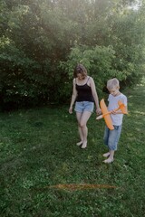 Fototapeta premium A mother and her son with hearing aids launch a paper airplane in a park, a heartwarming moment of inclusive play and bonding in nature. Perfect for disability awareness and family lifestyle content