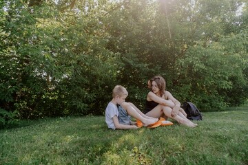 A mother and her son with hearing aids launch a paper airplane in a park, a heartwarming moment of...