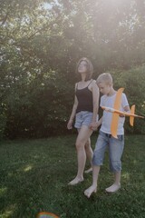 A mother and her son with hearing aids launch a paper airplane in a park, a heartwarming moment of...
